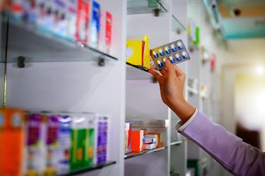 person stacking shelves with pharmaceuticals in boxes