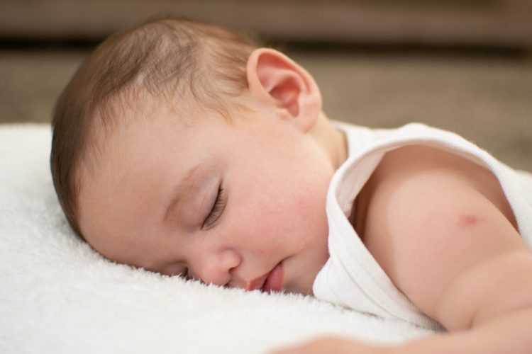 Baby sleeping after a BCG vaccine - red lump at site of injection visible on upper arm