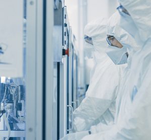 Biopharma manufacturing facility workers dressed in cleanroom gear operating machinery