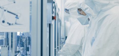 Biopharma manufacturing facility workers dressed in cleanroom gear operating machinery