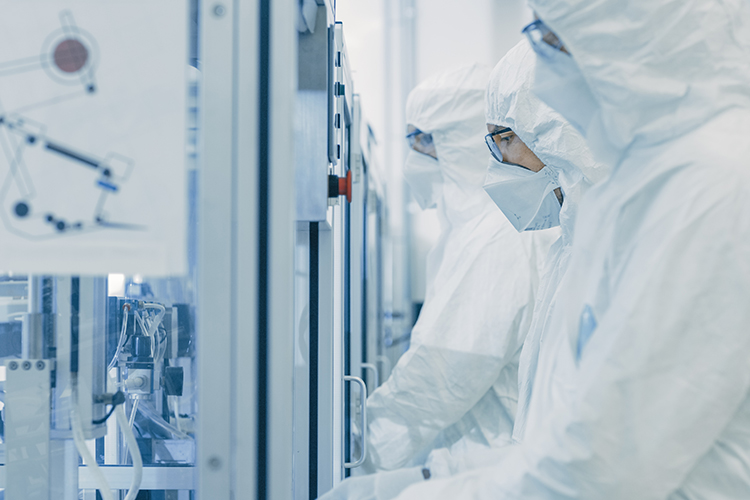 Biopharma manufacturing facility workers dressed in cleanroom gear operating machinery