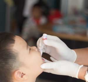 Male Thai child receiving oral polio vaccine from healthcare worker [Credit: frank60 / Shutterstock.com].