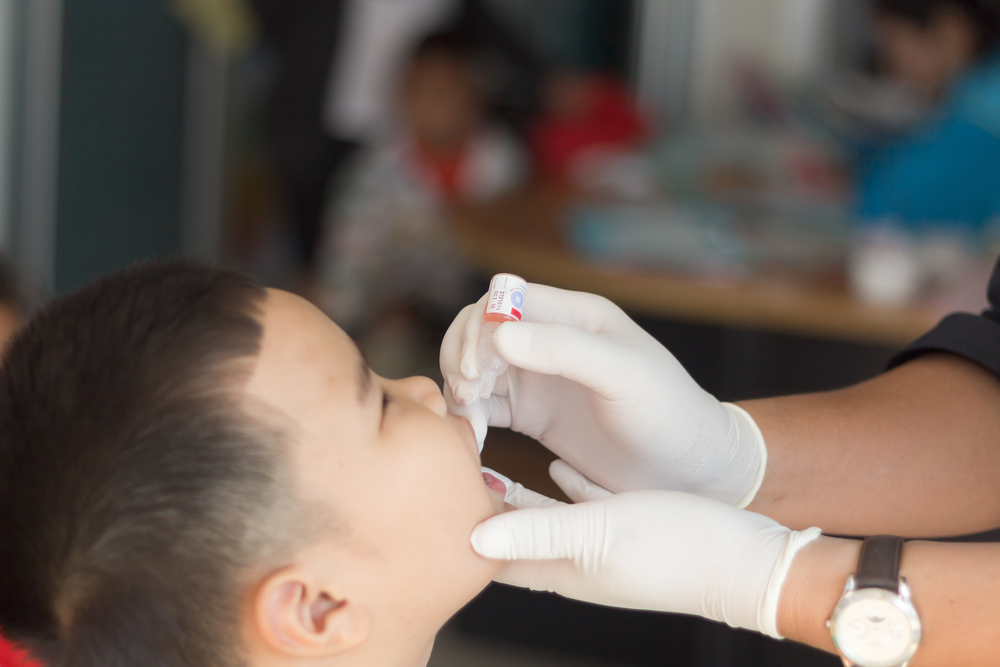 Male Thai child receiving oral polio vaccine from healthcare worker [Credit: frank60 / Shutterstock.com].