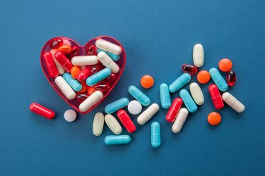 different colours of capsules in a heart-shaped dish - idea of access to healthcare/medicine