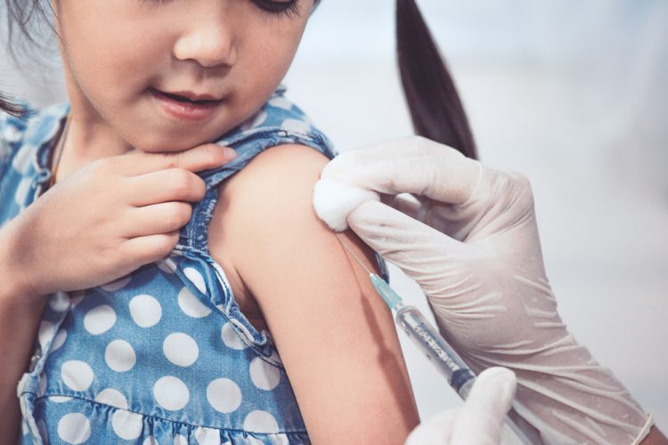 octor injecting vaccination in arm of little girl