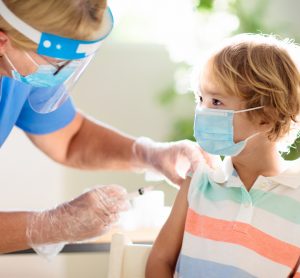 Doctor in Personal Protective Equipment giving a child a COVID-19 Vaccine