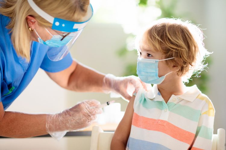 Doctor in Personal Protective Equipment giving a child a COVID-19 Vaccine