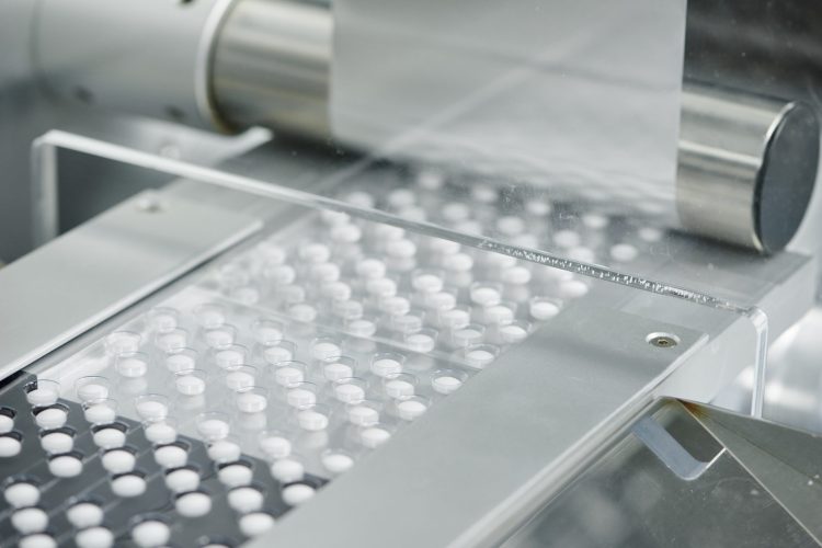 White tablets being sealed into blister packages