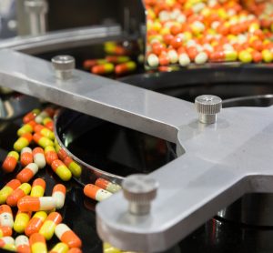Bright orange and yellow capsules on a production line at a pharmaceutical factory - idea of pharma manufacturing