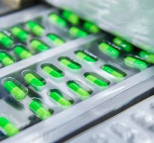 Green medicine capsules on a production line - idea of pharmaceutical manufacturing