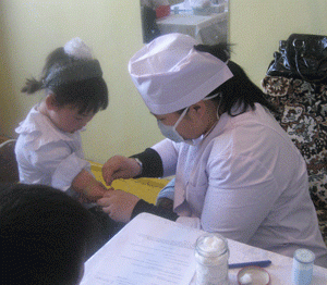Phlebotomist taking a blood sample from a Mongolian child