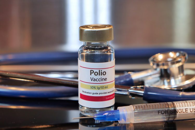 Vial labelled 'POLIO VACCINE' surrounded by a stethoscope and a syringe