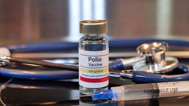 Vial labelled 'POLIO VACCINE' surrounded by a stethoscope and a syringe