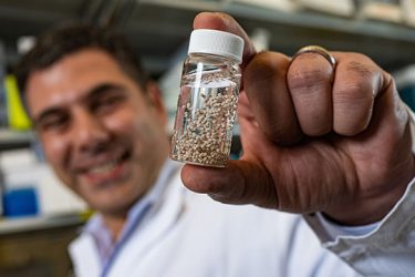 Rice University bioengineer Omid Veiseh with a vial of bead-like implants his lab invented to serve as anti-cancer drug factories. Veiseh and colleagues showed the implants could eradicate ovarian and colorectal cancer in mice in as little as six days [Credit: Photo by Jeff Fitlow/Rice University].