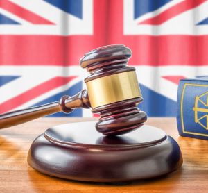 gavel and law book on a table in front of the Union Jack - idea of UK regulations