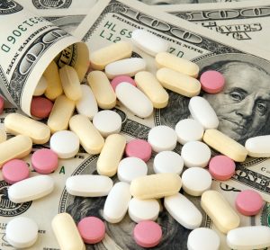 tablets spilling out of a roll of US $100 bills