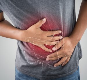 Close up of a man holding his stomach with the outline of a large intestine drawn on it and glowing in red - idea of gastrointestinal issues like ulcerative colitis