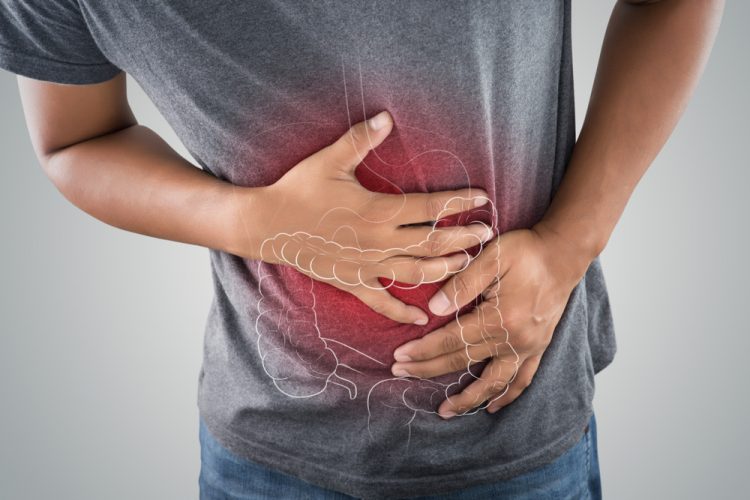 Close up of a man holding his stomach with the outline of a large intestine drawn on it and glowing in red - idea of gastrointestinal issues like ulcerative colitis