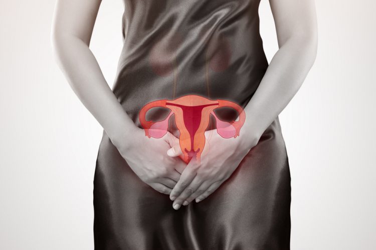 Woman with hands over her lower stomach and an anatomical drawing of a uterus above them - idea of women's health issues, such as endometriosis