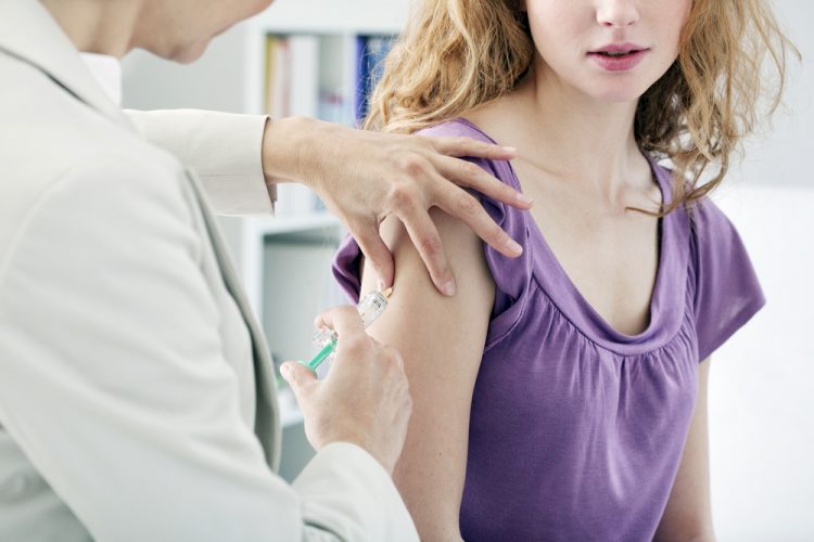 close up of an adolescent girl receiving a vaccine from a doctor in a white coat - idea of COVID-19 vaccines approved in people aged 12 years and over