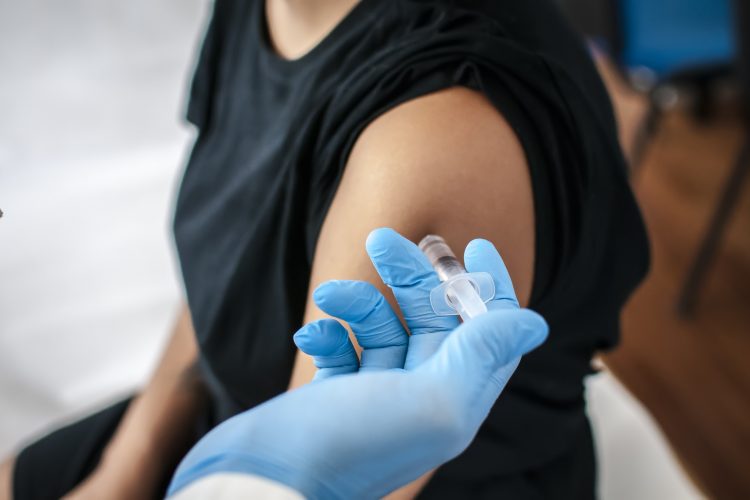 adolescent woman recieving a vaccination in the top of her arm