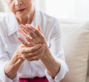 Elderly woman rubbing her hand -idea of joint pain due to arthritis