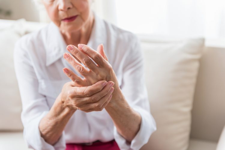 Elderly woman rubbing her hand -idea of joint pain due to arthritis