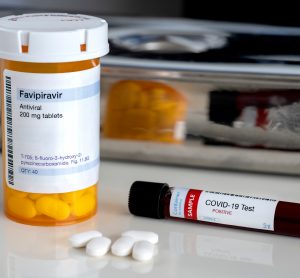 pill bottle lavelled 'favipiravir (Avigan) 200mg tablets' next to three white tablets and a blood sample vial