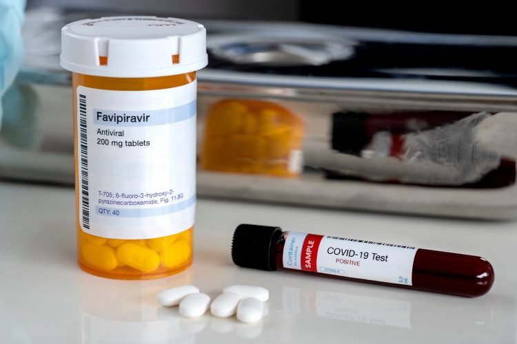 pill bottle lavelled 'favipiravir (Avigan) 200mg tablets' next to three white tablets and a blood sample vial