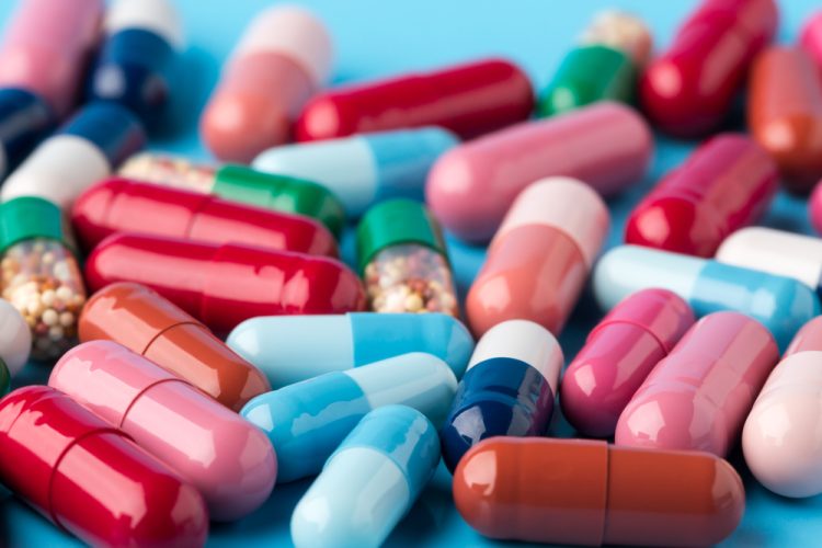 Colorful different medicine capsules on blue background