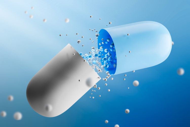 Large open white and blue capsule with medicine leaking from it over a blue background