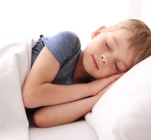 Child sleeping on side in white bedroom