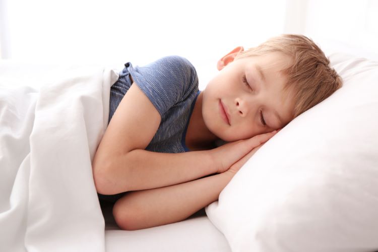 Child sleeping on side in white bedroom