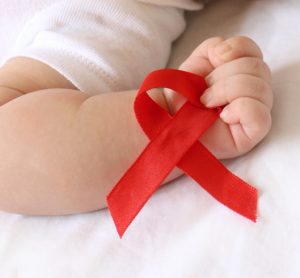 AIDS awareness red ribbon held in the hand of a small baby