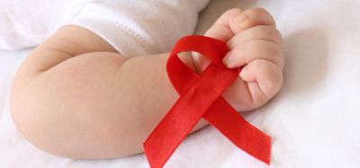 AIDS awareness red ribbon held in the hand of a small baby