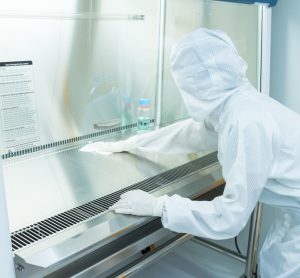 A scientist in sterile coverall gown using alcohol 70% and cleanroom wipes for cleaning Biological safety cabinet(BSC.) in laboratory