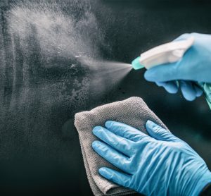 Close up of person's hands spraying and wiping a metal surface - idea of cleaning