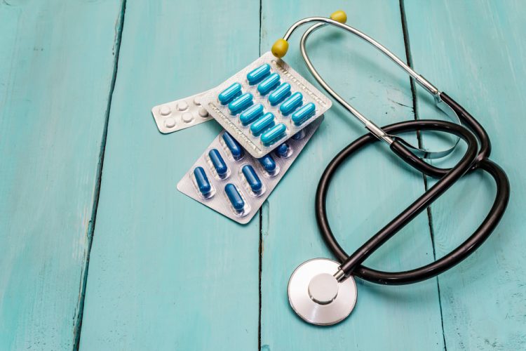 concept of clinical trials - stethoscope and pill packets on a wooden board background