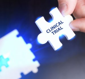 person placing a glowing puzzle piece labelled clinical trial into a jigsaw puzzle