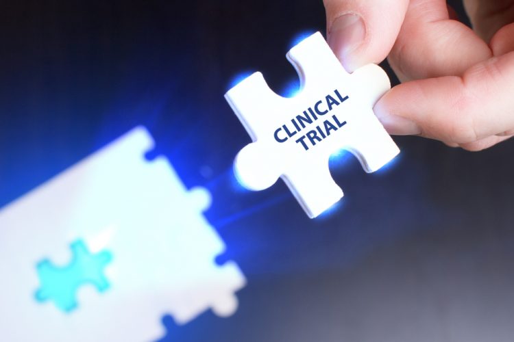 person placing a glowing puzzle piece labelled clinical trial into a jigsaw puzzle