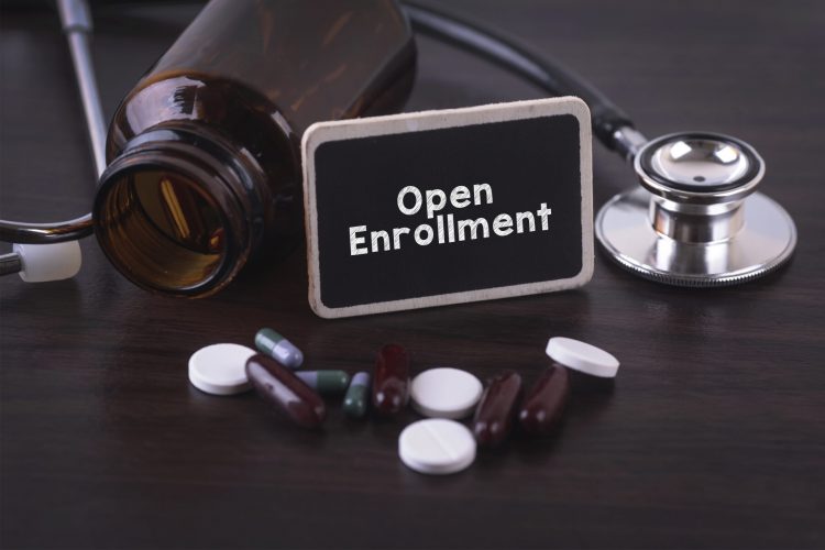 medicine bottle with stethoscope and black and white tables surrounding a sign saying 'open enrollment'