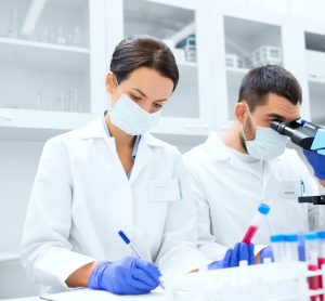 scientists performing tests on blood samples using a microscope in a lab