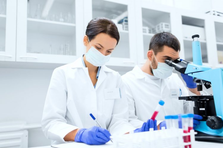 scientists performing tests on blood samples using a microscope in a lab