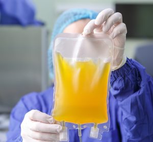 blood plasma in an IV bag held up by doctor wearing PPE