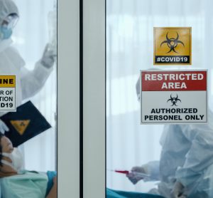 doctors in Personal Protective Equipment (PPE) in the room of a hospitalised COVID-19 patient