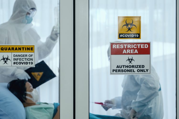 doctors in Personal Protective Equipment (PPE) in the room of a hospitalised COVID-19 patient