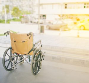 Empty wheelchair facing out towards a street - idea of disability or disorders such as myasthenia gravis that may leave people immobile