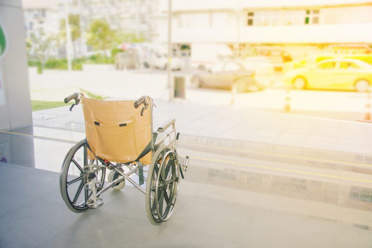 Empty wheelchair facing out towards a street - idea of disability or disorders such as myasthenia gravis that may leave people immobile