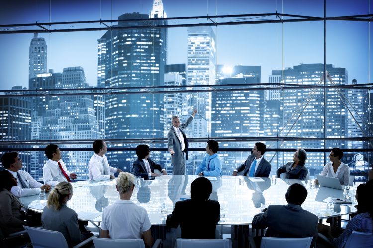 boardroom with huge table surrounded by a diverse group of people