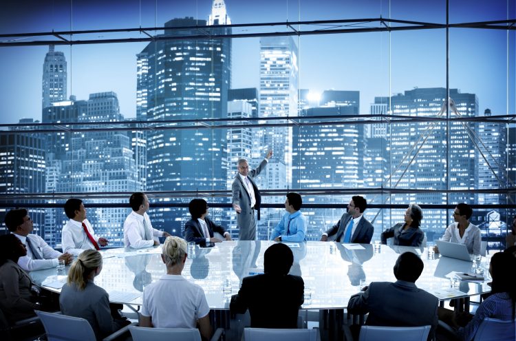 boardroom with huge table surrounded by a diverse group of people